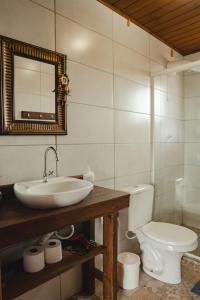 a bathroom with a toilet and a sink and a mirror at Pousada Canto do Rosa in Praia do Rosa