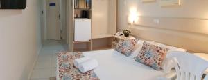 a bedroom with a white bed with pillows at Pousada Morada do Pescador in Bombinhas