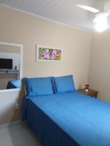 - une chambre dotée d'un lit avec des draps bleus et un miroir dans l'établissement Aluguel temporada no Centro de Búzios, à Búzios