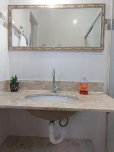 eine Badezimmertheke mit einem Waschbecken und einem Spiegel in der Unterkunft Aluguel temporada no Centro de Búzios in Búzios