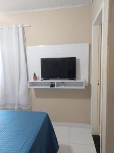 - une chambre avec une télévision murale et un lit dans l'établissement Aluguel temporada no Centro de Búzios, à Búzios