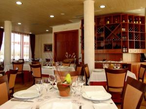 un restaurante con mesas blancas y sillas con copas de vino en Complejo El Carrascal, en Muñana
