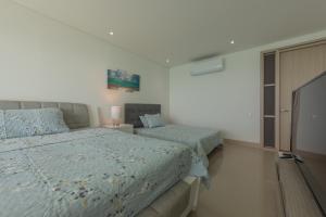 1 dormitorio con 2 camas y TV. en MURANO ELITE NEW OCEAN FRONT DUPLEx, en Cartagena de Indias