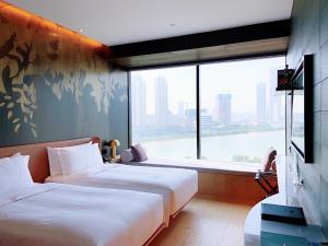 dwa łóżka w pokoju z dużym oknem w obiekcie The Macau Roosevelt Hotel w mieście Makau