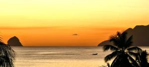 una spiaggia con una barca nell'oceano al tramonto di Martinique hostel a Sainte-Luce