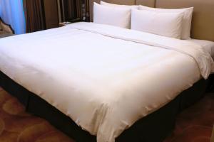 a large white bed with white sheets and pillows at Shangri-La Qufu in Qufu