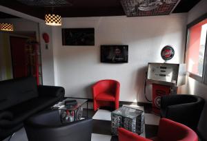 een woonkamer met een bank en een rode stoel bij Enzo Hotels Pont-a-Mousson by Kyriad Direct in Pont-à-Mousson