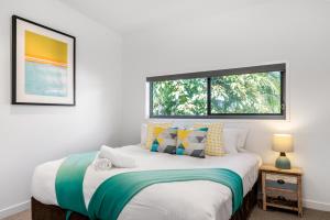 a bedroom with a large bed with a window at KoKos Beach House 3 in Byron Bay