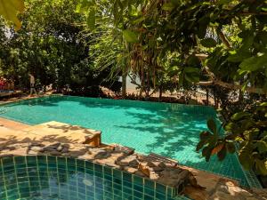a swimming pool with blue water and trees at The Narima - SHA Plus in Ko Lanta