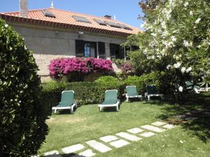 a row of lawn chairs in front of a garden at Hotel Playa de Vigo in Vigo