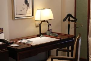 a desk in a hotel room with a lamp on it at Shangri-La Qufu in Qufu
