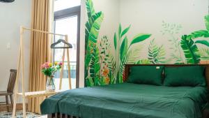 a bedroom with a green bed with a tropical wallpaper at Cherry Apartment - Thao Dien Centre in Ho Chi Minh City