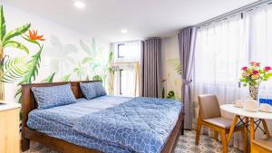 sypialnia z niebieskim łóżkiem, stołem i oknem w obiekcie Cherry Apartment - Thao Dien Centre w Ho Chi Minh