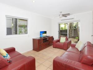 a living room with two red couches and a television at Mayfield 23 in Alexandra Headland