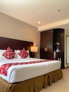 a bedroom with a large bed with red pillows at Alpa City Suites Hotel in Cebu City