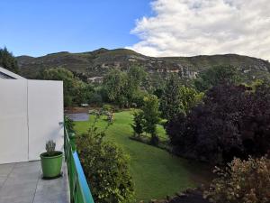a balcony with a green yard with mountains in the background at Clarens on Collett in Clarens