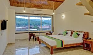 a bedroom with a bed and a large window at Hotel Lake Paradise Mahabaleshwar in Mahabaleshwar