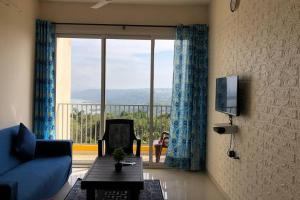 a living room with a blue couch and a large window at Birdsnest Seaview Holiday Home in Dabolim