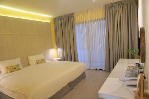a hotel room with a large bed and a window at Sook Hotel in Ranong