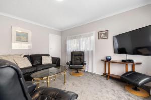 a living room with a couch and a tv at Pomare Cottage - Rotorua Holiday Home in Koutu