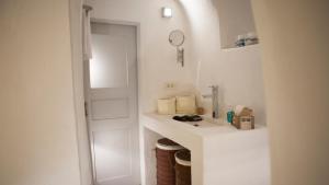 une salle de bain blanche avec un lavabo et un miroir dans l'établissement Oia, Finikia Cave House, à Oia