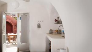 - une cuisine avec des murs blancs et un comptoir blanc dans l'établissement Oia, Finikia Cave House, à Oia