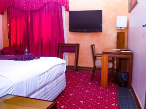 a hotel room with a bed and a table and a television at Hotel Fleur De Lys Almadies in Dakar