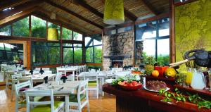a restaurant with tables and chairs and a fireplace at Kariega Game Reserve Main Lodge in Kenton on Sea