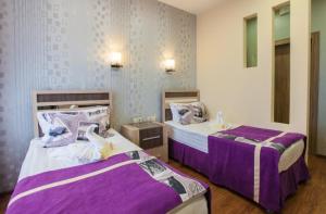 two beds in a room with purple sheets at Sanatory Rassvet in Berdsk