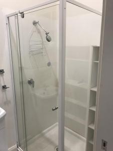 La salle de bains est pourvue d'une douche avec une porte en verre. dans l'établissement Belmont Palms Motel, à Belmont
