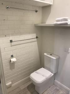 a white bathroom with a toilet and a shelf at Belmont Palms Motel in Belmont