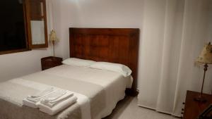 a bedroom with a white bed with a wooden headboard at Las Casitas de Papel in Ampudia