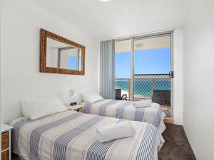 two beds in a room with a view of the ocean at Ebbtide 38 On The Beach in Forster