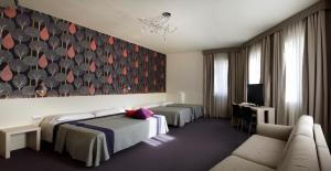 ヴィチェンツァにあるホテル コンチネンタルのベッド2台とソファが備わるホテルルームです。