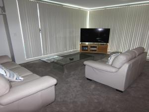 een woonkamer met 2 banken en een flatscreen-tv bij Twin Pines 301 CBD Location in Forster
