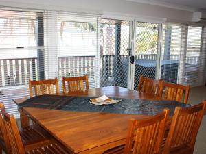 uma mesa de jantar e cadeiras com uma mesa de madeira e janelas em Tokelau 2 Tuncurry Townhouse em Forster