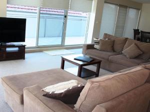 a living room with a couch and a flat screen tv at The Reef 103 Lakeside in Forster