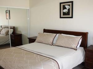 a bedroom with a bed with a mirror on the wall at The Reef 103 Lakeside in Forster