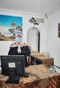 uma pessoa que usa uma máscara facial em frente a um computador em Rumah Larasati em Malang
