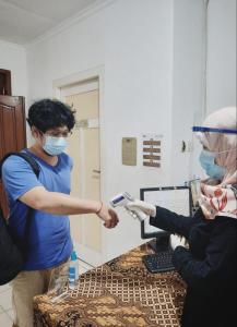 une personne dans une pièce avec une personne tenant une machine dans l'établissement Rumah Larasati, à Malang