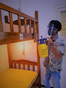 mężczyzna stojący obok łóżka piętrowego trzymający butelkę w obiekcie Rumah Larasati w mieście Malang