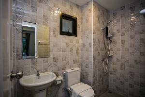 ein Badezimmer mit einem Waschbecken, einem WC und einem Spiegel in der Unterkunft โรงแรมกอดหมอน in Nakhon Pathom