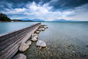 a wooden dock in the water with rocks on the shore at Ferienappartement in der Wolfsgrube-Rambichler in Chieming