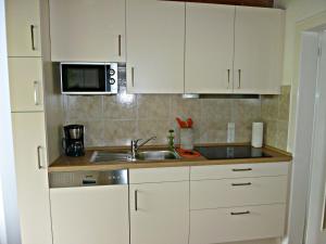 a kitchen with white cabinets and a sink and a microwave at Ferienappartement in der Wolfsgrube-Rambichler in Chieming