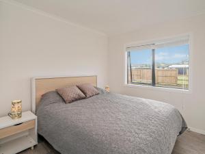 a white bedroom with a bed and a window at Seabliss - Cooks Beach Holiday Home in Cooks Beach