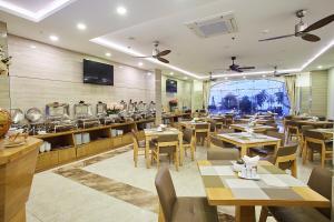 Un restaurante con mesas y sillas y un gran ventanal. en Boss Hotel, en Nha Trang