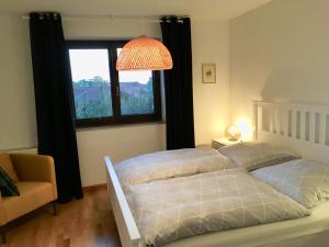 Duas camas num quarto com uma janela e um candeeiro. em Haus Mali em Chieming