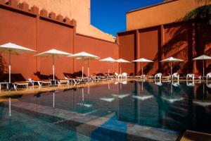 a swimming pool with umbrellas and chairs and a building at Diwane Hotel & Spa Marrakech in Marrakesh