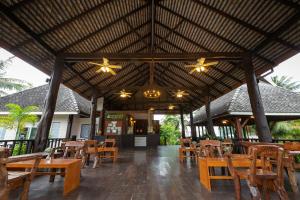 a restaurant with wooden tables and chairs and a roof at Nakara Long Beach Resort - SHA Extra Plus in Ko Lanta