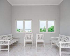 RedDoorz @ City Park Medoho Semarang في Alastuwo: غرفة بثلاث كراسي بيضاء ونوافذ